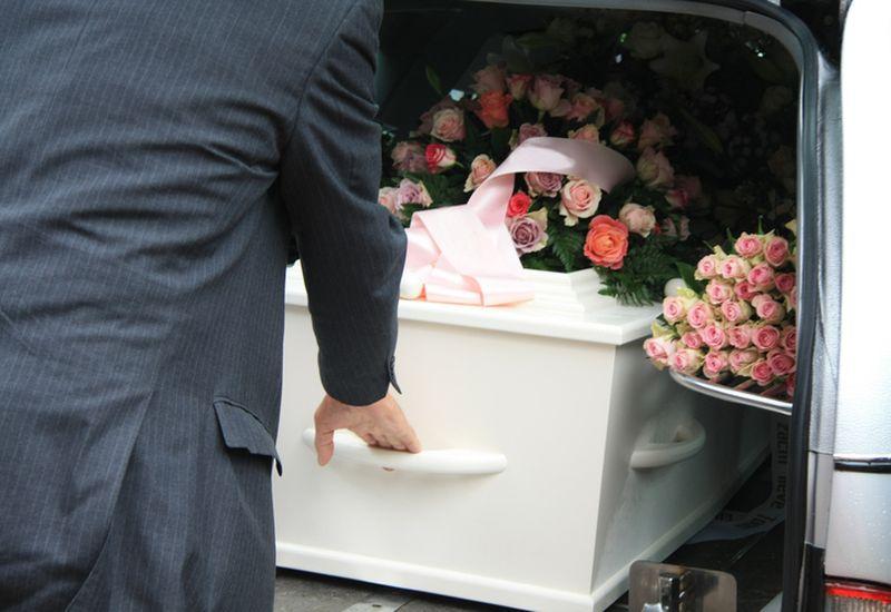 wyjmowanie trumny z samochodu pogrzebowego